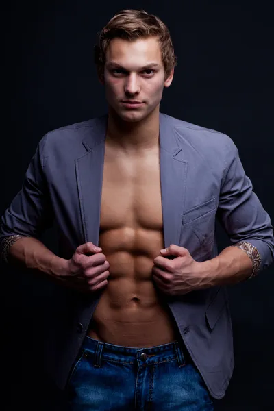 Giovane uomo macho sexy con giacca aperta su sfondo scuro — Foto Stock