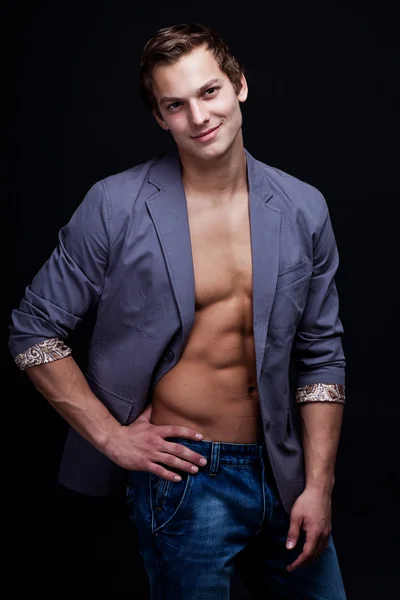 Giovane uomo macho sexy con giacca aperta su sfondo scuro — Foto Stock