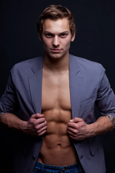 Young sexy macho man with open jacket over dark background — Stock Photo, Image