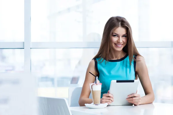 Jonge gelukkig vrouw met behulp van tablet pc in een café — Stockfoto