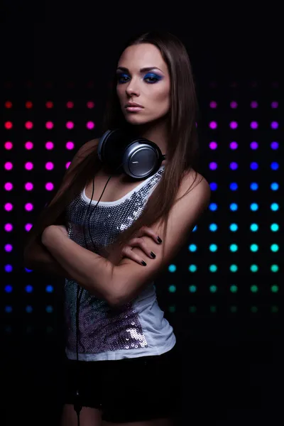 Giovane donna DJ con le cuffie su sfondo discoteca — Foto Stock