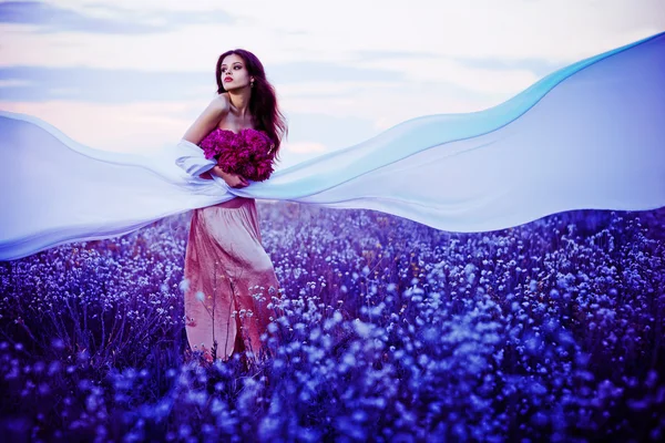 Hermosa mujer en el campo de atardecer con flores y fabri blanco —  Fotos de Stock