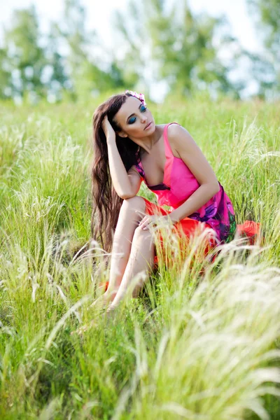 Retrato ao ar livre de jovem mulher bonita em vestido vermelho e flor em seu cabelo — Fotografia de Stock