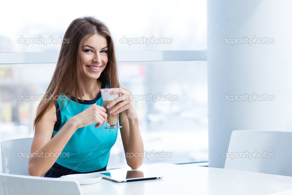 young happy woman using tablet computer in a cafe
