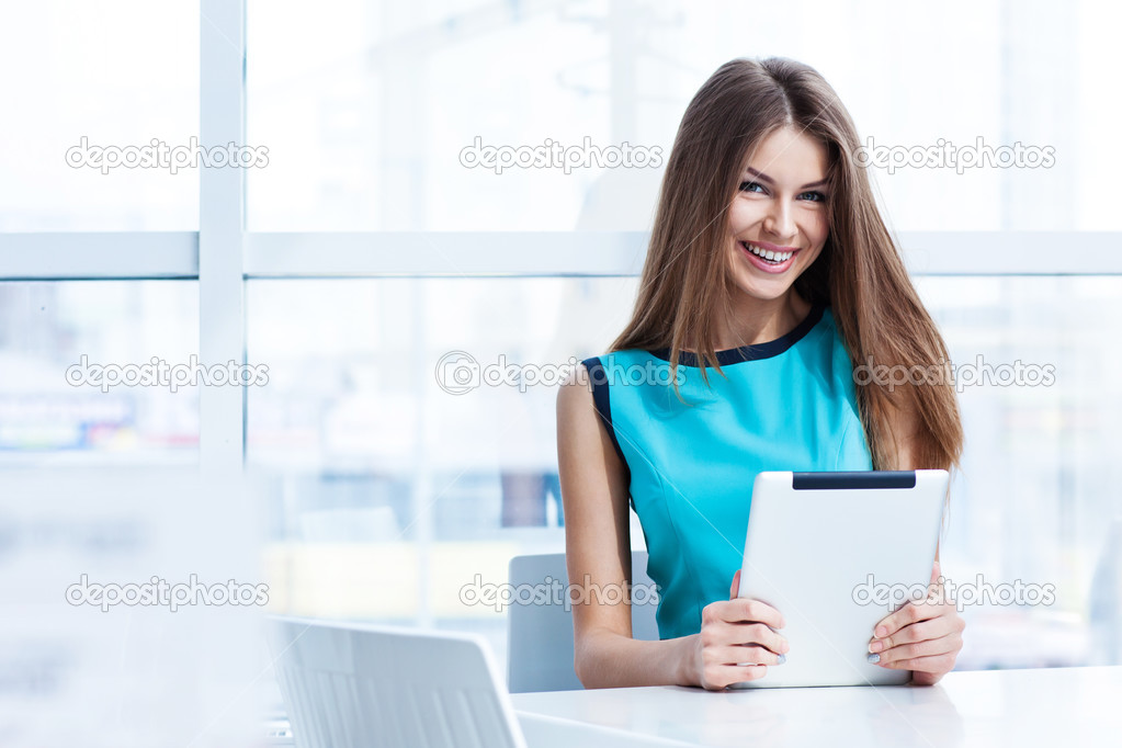 young happy woman using tablet computer in a cafe