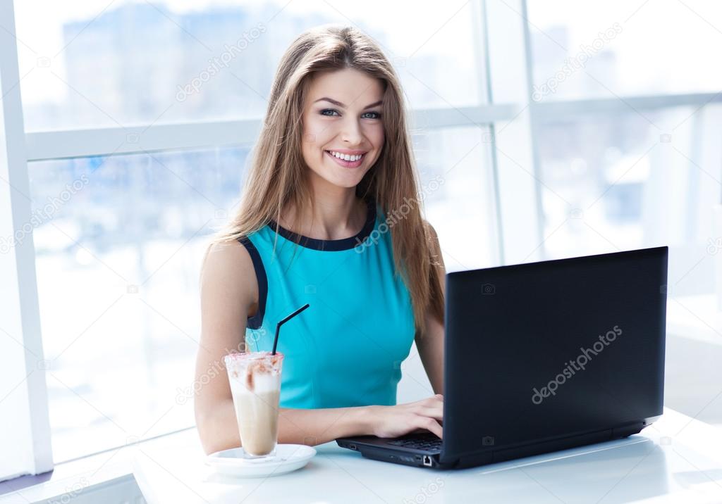 Portrait of beautiful smiling woman sitting in a cafe with laptop