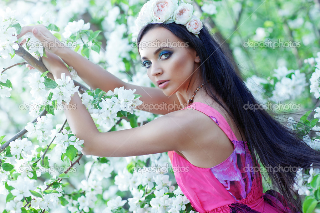 Woman with a flower wreath near the blossom apple-tree