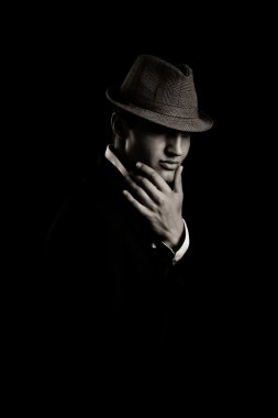 Genç gangster karanlıkta şapka ile düşük anahtar portresi.