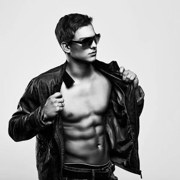 Young handsome macho man in sunglasses with open leather jacket — Stock Photo, Image