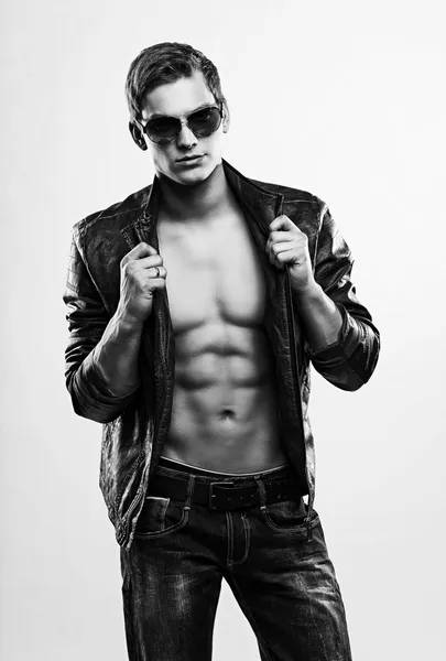 Young handsome macho man in sunglasses with open leather jacket — Stock Photo, Image