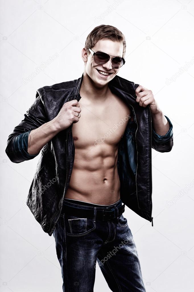 Young handsome macho man in sunglasses with open leather jacket