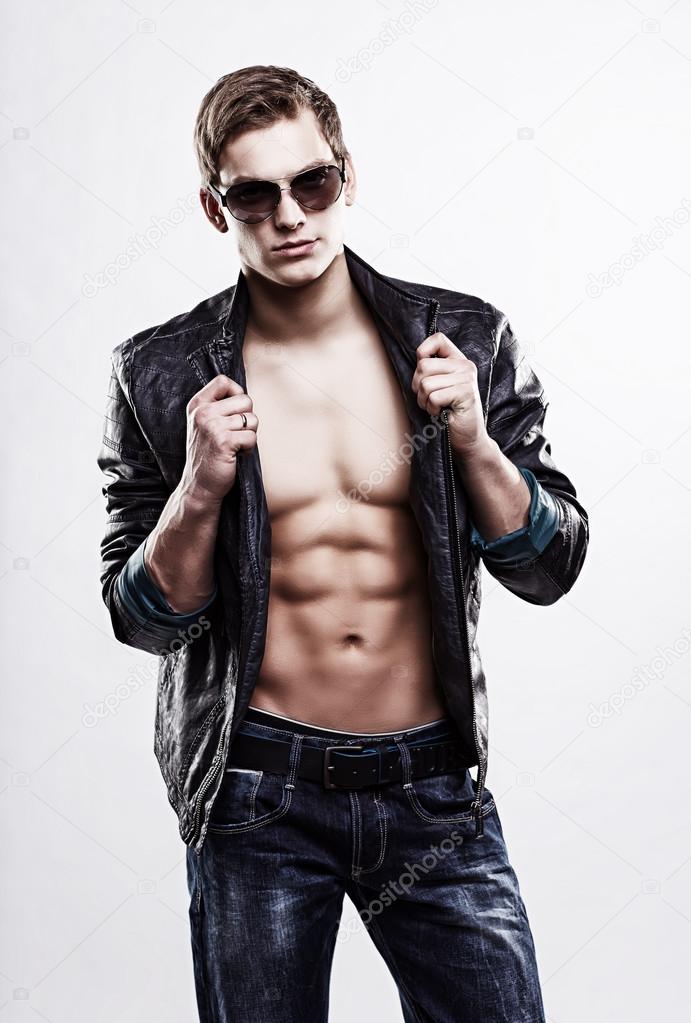 Young handsome macho man in sunglasses with open leather jacket