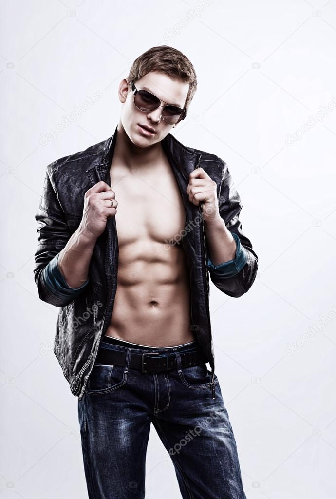 Young handsome macho man in sunglasses with open leather jacket