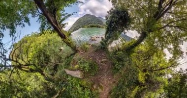 Uzayın eğriliğiyle küçük bir gezegen dönüşümü. Ormandaki dağlarda göl kenarında soyut bükülme ve dönen küresel panorama.