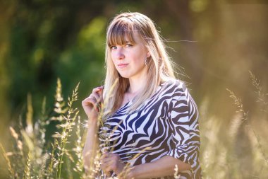 Güzel kız ormanın çalılıklarında duruyor.