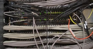 Modern sunucuda çok sayıda kablo ve kablo ve ağ ekipmanı yanıp sönen yeşil ışıklar ve veri merkezinde raftaki optik kesiciler