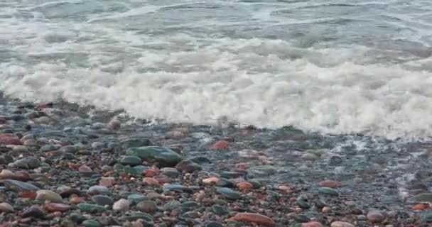 嵐の中海岸で泡の波が力強く砕け小石や小石の海岸を洗い — ストック動画