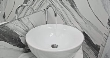 Pahalı banyodaki soğuk ve sıcak suyu açmak ve düzenlemek için musluk ve lavabo ile metal su musluğundan akan su.. 