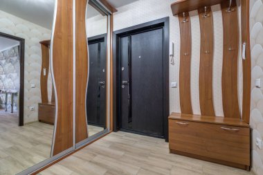 Kapıları, dolapları, rafları ve aynası olan modern apartmanların giriş salonunun içinde uzun bir koridor. 