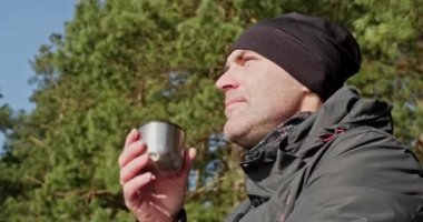 Kış giysileri içindeki insan portremizi kapatır nehir kıyısında çam ormanında çay içer ve dinlenir. 