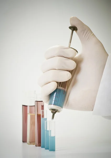 Scientist holding old injection with blue chemical. — Stock Photo, Image