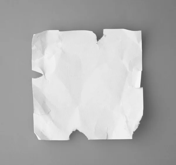 White broken and creased paper note isolated on a gray backgroun — Stock Photo, Image