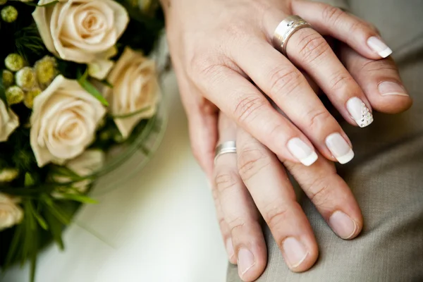 Handen van een jong koppel met bruiloft ringen. — Stockfoto