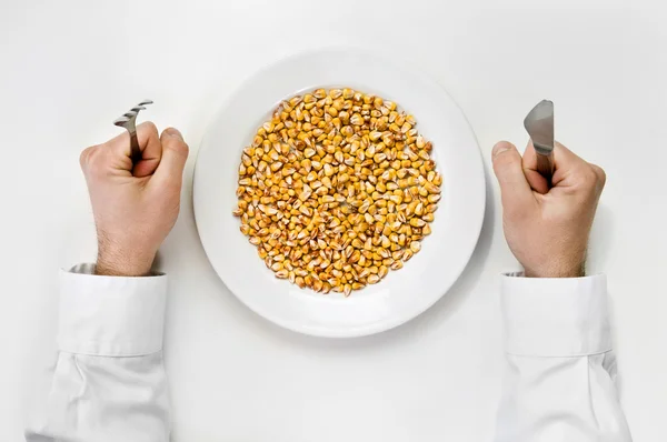 Corn meal. Plate of dry corn with fork and knife isolated on whi — Stock Photo, Image