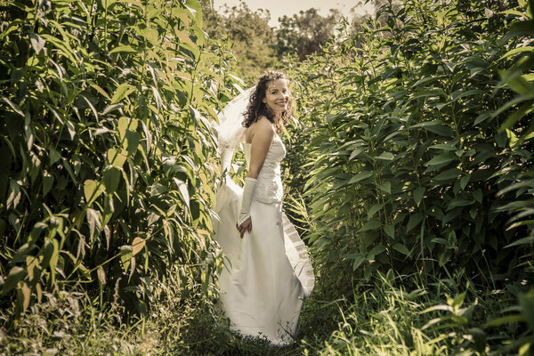 Happy beautiful bride standing in grass and smilling.