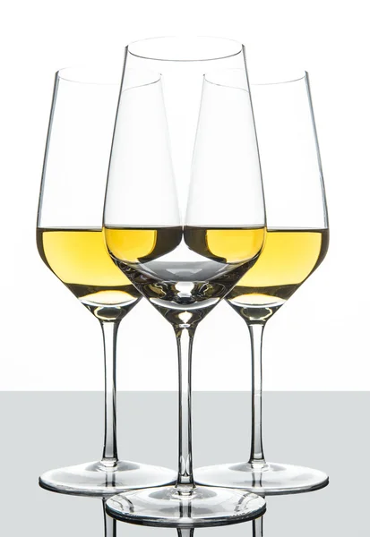 Formación de copas de vino blanco detrás de la otra. con reflejo —  Fotos de Stock