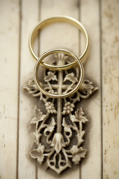 Anéis de casamento dourados na cruz esculpida — Fotografia de Stock