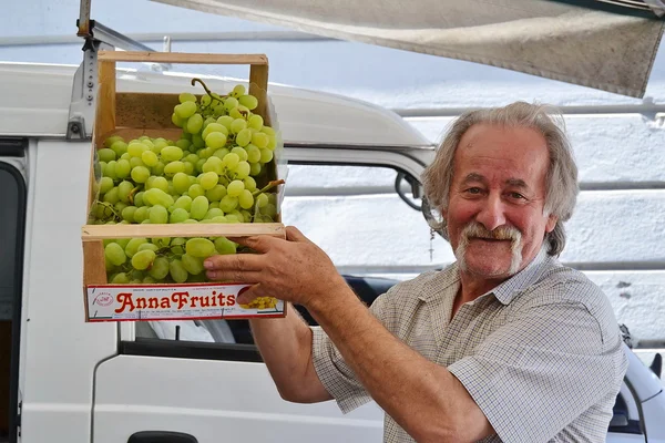 Fruit vendor shows a box of grapes — Stock Photo, Image