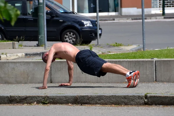 En mand laver gymnastik på gaden - Stock-foto