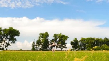 Yaz mevsiminde büyük yeşil bir alanda hoplayıp zıplayan bir kız.