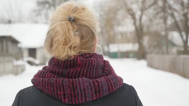 Дівчина з світлим волоссям йде по вулиці взимку — стокове відео