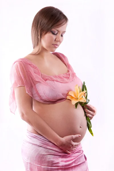 Pregnant woman holding belly and flower — Stock Photo, Image