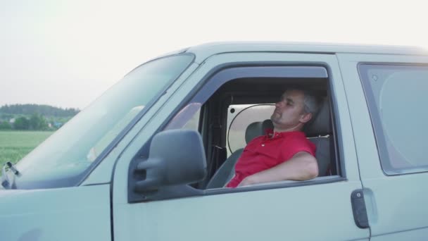 Уставший мужчина с бородой отдыхает с закрытыми глазами за рулем минивэна — стоковое видео