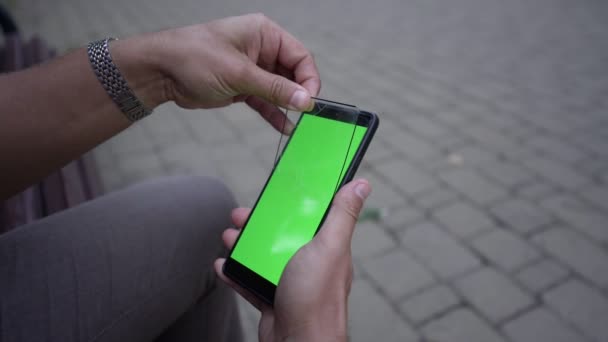 Человек удаляет треснувшее защитное стекло с экрана телефона — стоковое видео