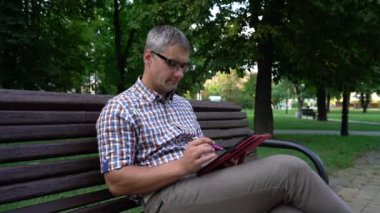 Gözlüklü adam tabletteki sosyal ağları kontrol ediyor