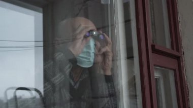 Maskeli tuhaf yaşlı bir adam dürbünlü casuslar.