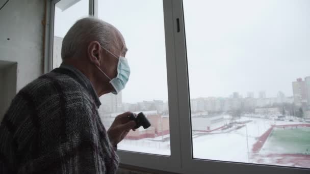 Homem velho concentrado em máscara facial olha através de binóculos — Vídeo de Stock