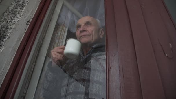 Депрессивный пожилой человек смотрит в устаревшее окно — стоковое видео