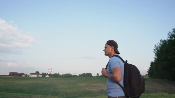 Sırt çantalı bir turist köyün yakınındaki yolda yürüyor. — Stok video