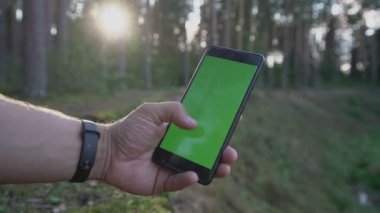 Yeşil renkli ekranlı akıllı telefonu tutan bir erkek.