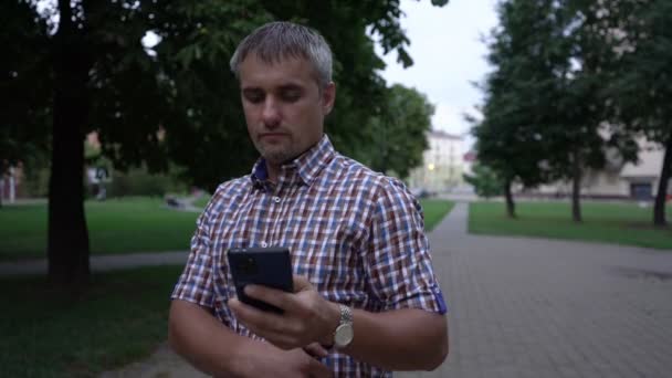 Homme montre téléphone avec écran vert à la caméra marche dans le parc — Video