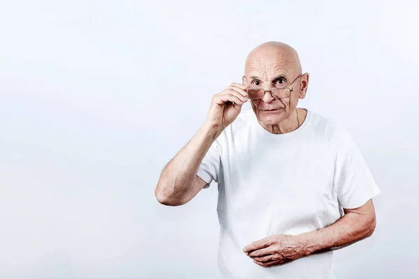 Olgun kel adam gözlüklerin altından bakıyor çerçevelere dokunuyor