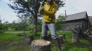 Kıdemli adam ağaç gövdesini titizlikle metal baltayla kesiyor.
