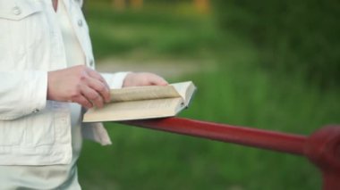 Rahat yetişkin kadın parkta kurgu kitapları okumaktan hoşlanıyor.