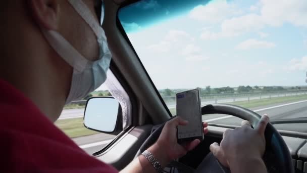 Водитель в защитной маске с помощью смартфона с навигационным приложением — стоковое видео