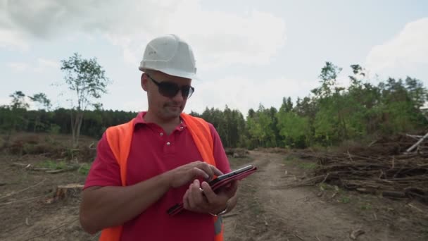 Man staat op ontbossingsplaats inspectiegebied en maakt opnamen in tablet — Stockvideo